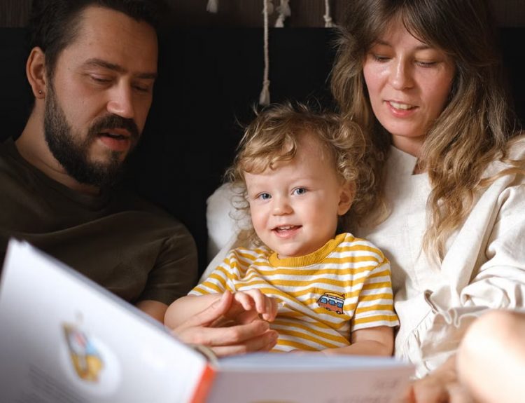 A happy family reading together, featuring parents and their smiling child enjoying a book indoors.