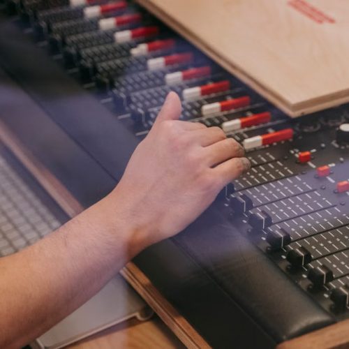 Close-up of an audio engineer's hand adjusting a mixing console in a recording studio.