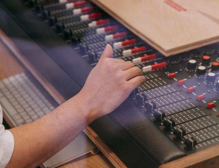 Close-up of an audio engineer's hand adjusting a mixing console in a recording studio.